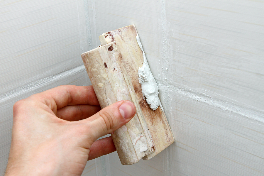 Worker sealing grout on bathroom tiles